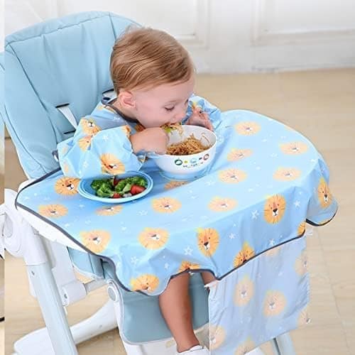 Creating a Baby Meal Plan 7 A toddler sitting in a high chair wearing a blue bib with a lion pattern, eating noodles from a bowl with some vegetables on the side.