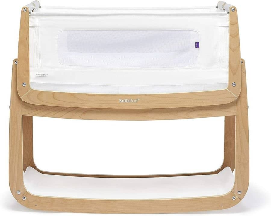 A wooden baby crib with a white fabric and mesh side panel, designed in a modern and compact style.